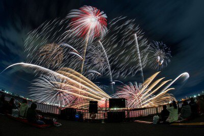 夜空に流れるように描かれる白と赤の花火
