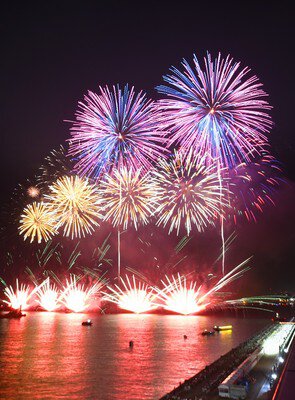 水面に映る花火が港の夜景を幻想的に演出