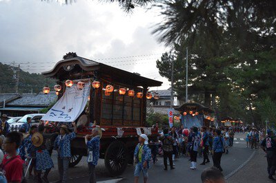夕暮れの町に灯る提灯と山車