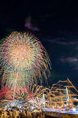「ライトアップされた海王丸と花火の光景
