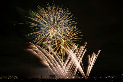 金色の光の軌跡が夜空に舞うスターマイン
