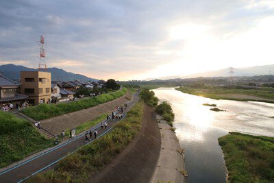会場へ向かう人々と紀の川の穏やかな夕景
