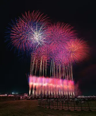 街の光と競演する華やかな花火