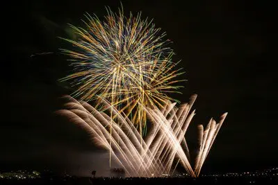 金色の光の軌跡が夜空に舞うスターマイン