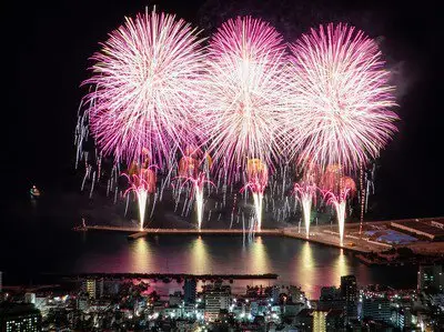 水面に映える鮮やかなピンクの光が夜空を染める