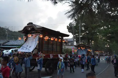 夕暮れの町に灯る提灯と山車